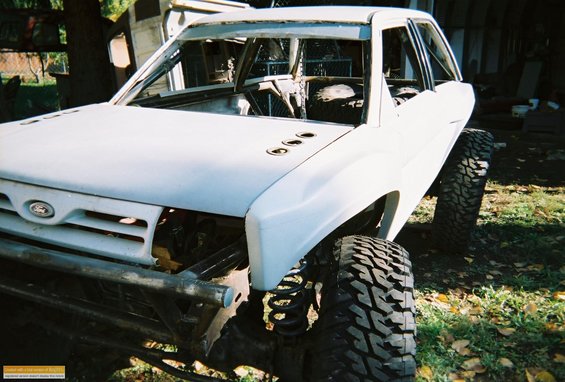 White 1991 Ford Bronco with large off-road tires and exposed engine bay, viewed from a 3/4 front angle
