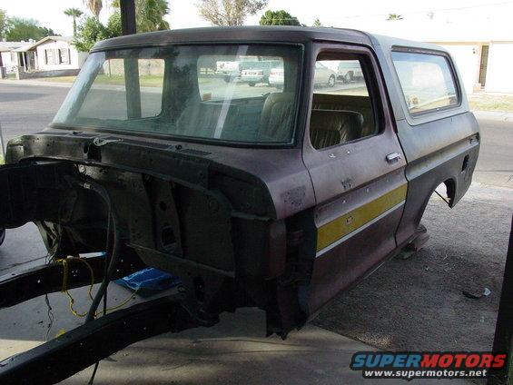 Maroon and yellow Ford Bronco body with missing front end and rear quarter panel, viewed from the front three-quarter angle