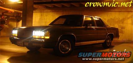 Dark sedan, 1988 Ford Crown Victoria LTD, parked indoors with headlights on