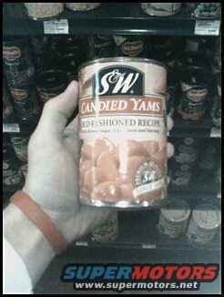 Hand holding a can of S&W Candied Yams. Shelves of canned goods in background