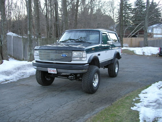 Lifted two-tone green and white Ford Bronco with chrome grille and aftermarket wheels