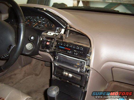 Car dashboard with radio removed, showing climate controls and gauges