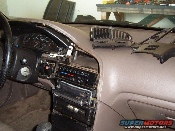Tan dashboard of a 1993 Mazda MX-6 with the center console disassembled, showing the radio and climate controls