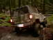 1987 Ford Bronco II - A camouflage 1987 Ford Bronco II navigates a muddy trail through a forest.
