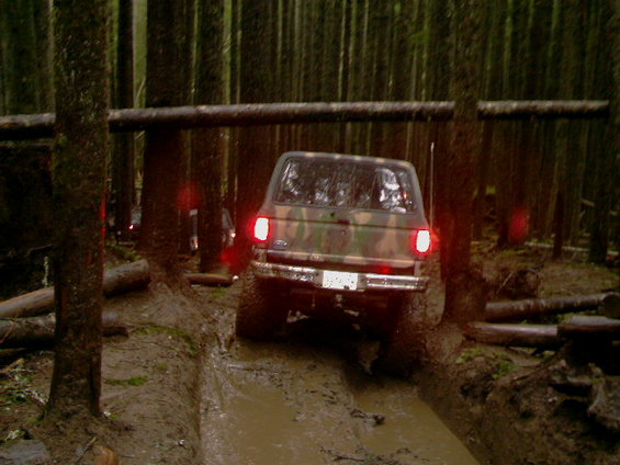 Camouflaged SUV navigating a muddy forest trail