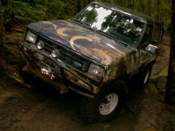 1987 Ford Bronco II with camouflage paint, stuck in mud, front winch visible