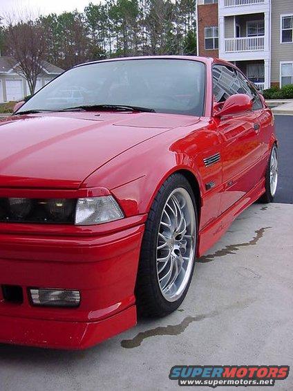 Red 1995 BMW M3 coupe with silver BBS wheels, parked on concrete with a puddle