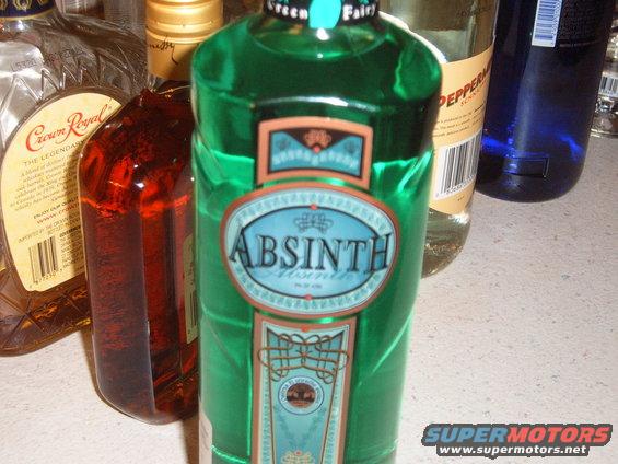 Green bottle of Absinthe with other alcohol bottles behind it