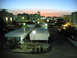1999 Mercury Grand Marquis - A street scene at dusk with multiple buildings and parked vehicles under a fading sky.