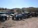 1984 Ford Bronco - A collection of modified off-road vehicles and trucks are gathered in a dry, outdoor area.