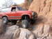 1984 Ford Bronco - This red Ford Bronco is shown off-roading on a steep, rocky incline.