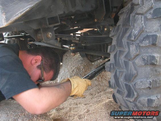 Guy working on the steering linkage of a large off-road vehicle