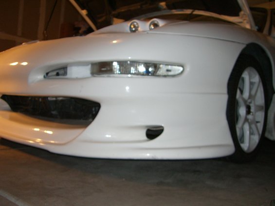 White sports car front bumper with fog lights and hood scoops