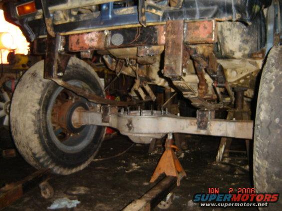 Rear axle and leaf spring suspension on a vehicle, supported by jack stands. Date stamp reads ION 2 2006