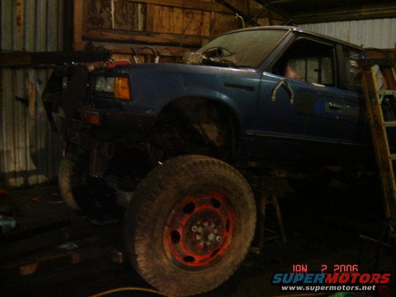Blue pickup truck with large tires and custom bumper, viewed from the front-right