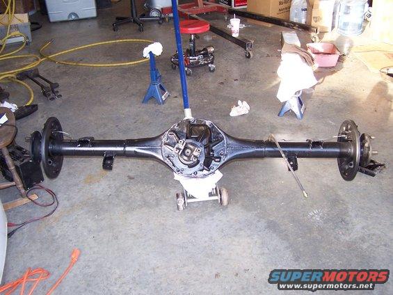 Rear axle assembly on garage floor, supported by a jack and jack stands