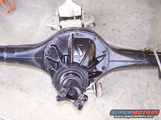 Black rear axle assembly with a "S" logo on the differential cover, resting on a jack