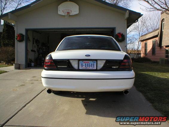 Rear view of a white 2000 Ford Crown Victoria parked in a driveway in front of a garage