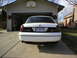 2000 Ford Crown Victoria - The rear of a white Ford Crown Victoria is shown parked in front of a garage with a basketball hoop above the door.
