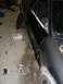 1993 Ford Probe - A black car is in a garage with its door removed, revealing the interior and some body damage.