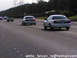 1999 Mercury Grand Marquis - A white police car is seen from behind on a highway with other vehicles.