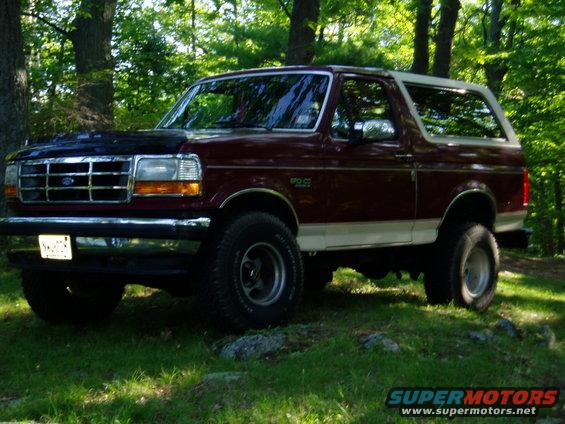 Maroon and white 1993 Ford Bronco parked in a wooded area