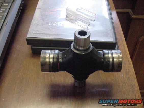Universal joint part on a wooden surface with DVDs in the background