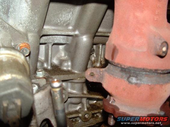 Engine block with oil stains and a red exhaust manifold