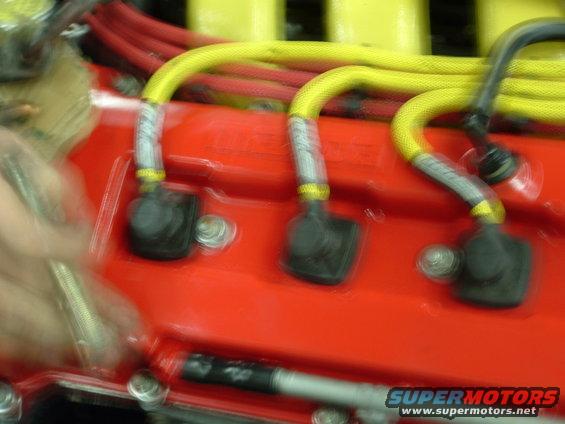 Close-up of yellow spark plug wires connected to black boots on a red engine component