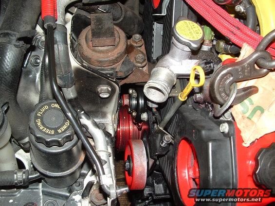 Engine bay detail showing red pulleys, power steering fluid cap, and coolant reservoir cap