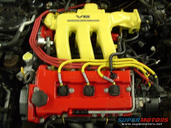 Engine bay with yellow V6 DOHC 24 VALVE intake manifold and red valve cover