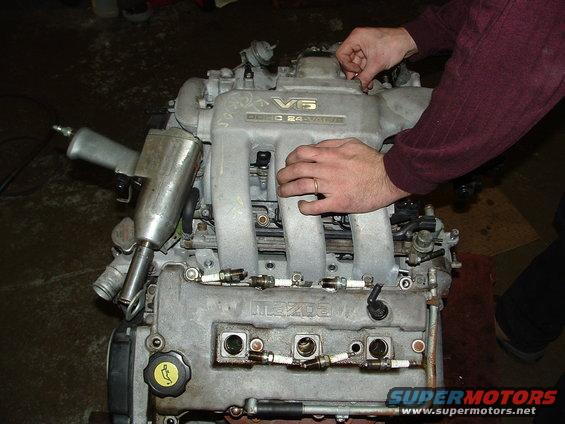Mazda V6 engine with "24 VALVE" text, being worked on by hands