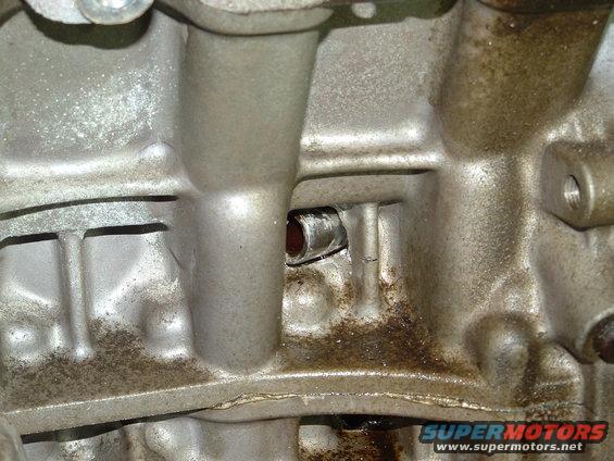 Close-up of a dirty, cast-iron engine block with a small hole