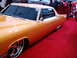 1986 Ford Bronco - This custom orange coupe features large chrome wheels and tinted windows, displayed indoors on a red carpet.