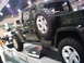 1986 Ford Bronco - A dark green Jeep Gladiator is displayed with its spare tire prominently mounted on the rear.