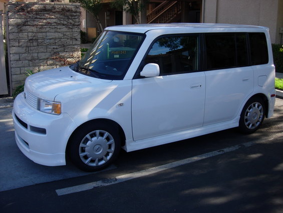 White 2006 Scion xB parked on asphalt, viewed from the front three-quarter angle. The car has tinted windows and aftermarket side skirts