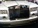 1986 Ford Bronco - Close-up of the distinctive chrome grille and headlights on a silver Rolls-Royce Phantom.