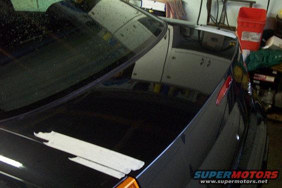 Black car trunk with white tape applied, showing reflections of garage interior
