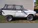 1974 Ford Bronco - Side view of a white 1974 Ford Bronco with a black soft top parked outdoors.