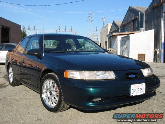 1995 Ford Taurus sedan, dark green, parked outside industrial buildings