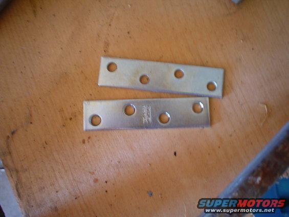 Two metal plates with holes on a wooden surface