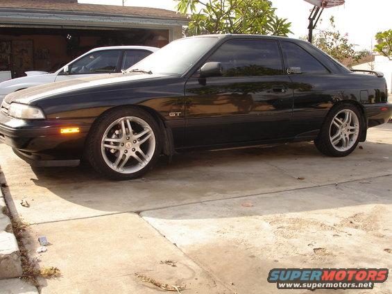 Black 1989 Mazda MX-6 GT parked in driveway, another car behind it