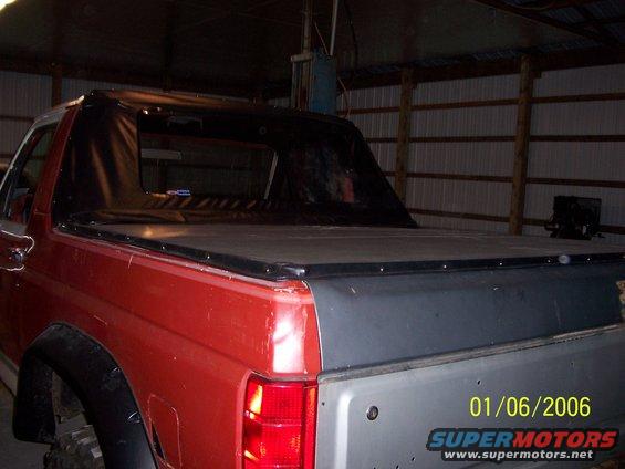 Red SUV with a black soft top and grey tailgate, seen from the rear