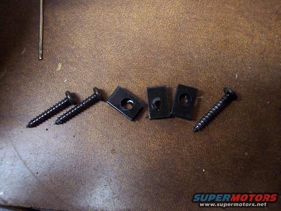 Black screws and U-nuts on brown textured surface