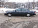 1999 Ford Crown Victoria - Dark blue sedan parked next to a river with snow on the banks.