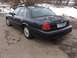 1999 Ford Crown Victoria - This dark sedan is parked on a dirt road with snow on the ground and trees in the background.