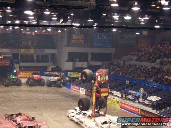 Monster trucks performing in an arena with a crowd watching