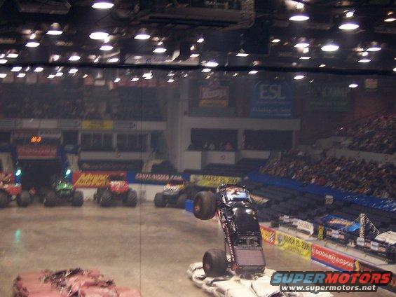 Monster truck on two wheels, performing a stunt in an arena