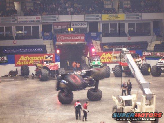 Monster trucks in an arena, one is upside down