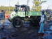 1995 Dodge 1500 - Several people stand around a green Unimog truck and a dark SUV in a muddy, wooded area.